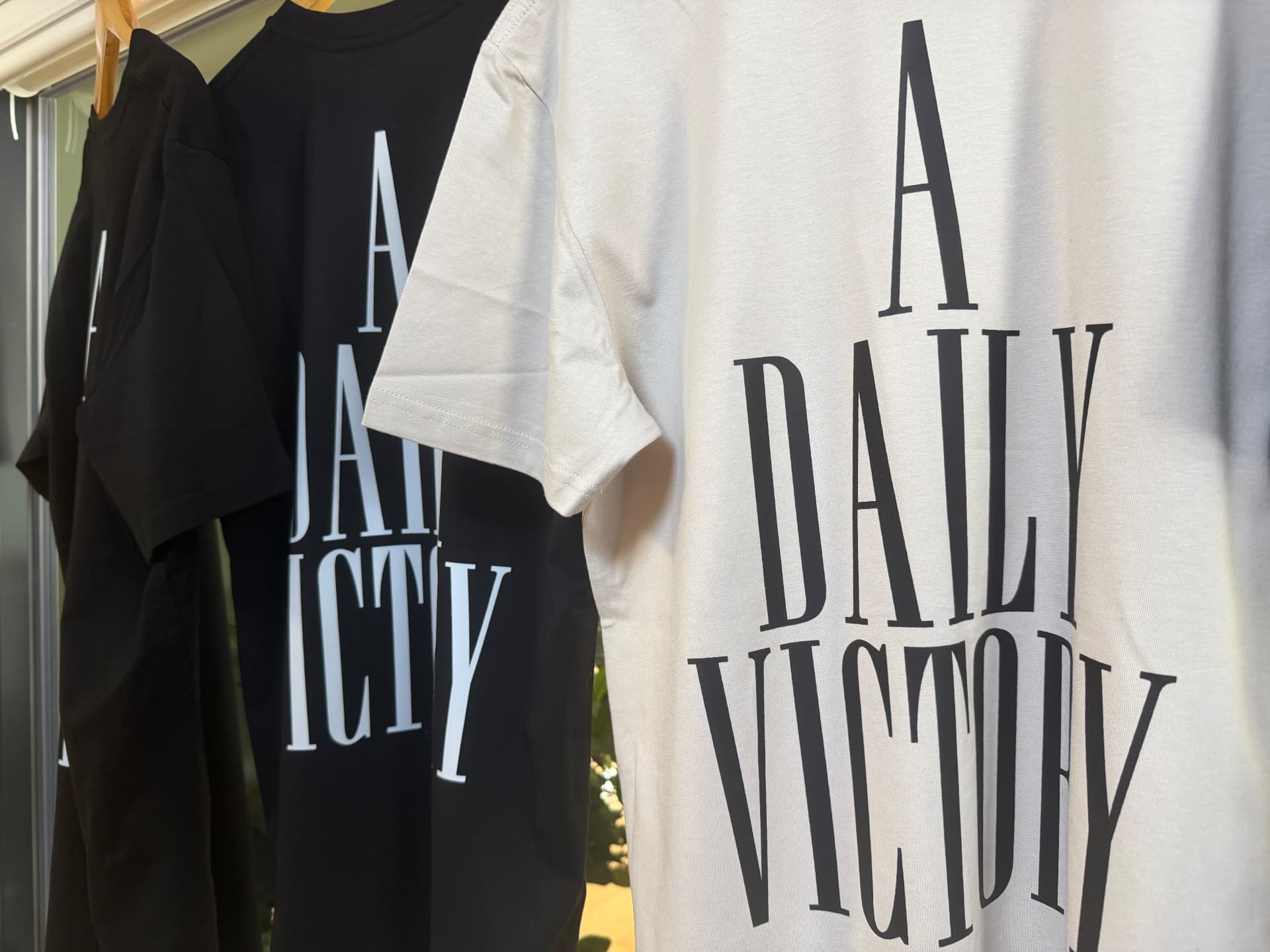 Black and white A Daily Victory T-shirts hanging outside